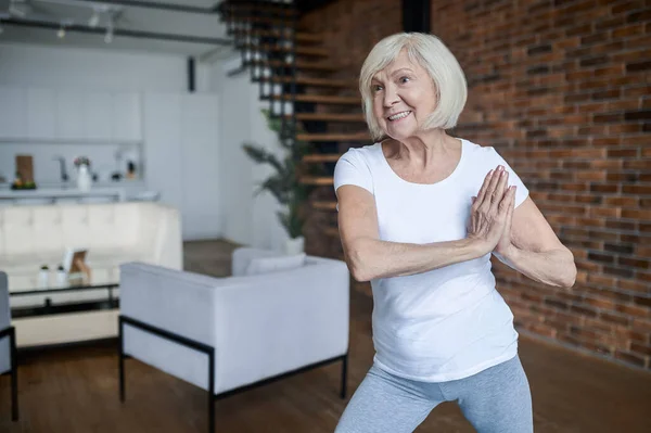 Slim aging žena dělá jógu doma — Stock fotografie