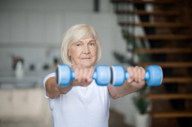 Active senior woman with dumbbells in hands doing her workout