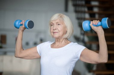 Active senior woman with dumbbells in hands doing her workout