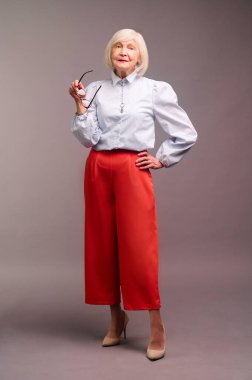 Elegant senior woman in white blouse and red pants