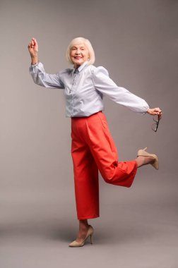 Happy senior woman in red pants and white shirt