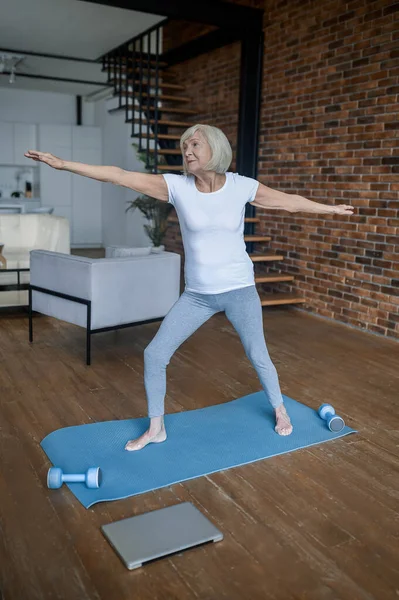 A senior woman standing in a warrior pose — 스톡 사진