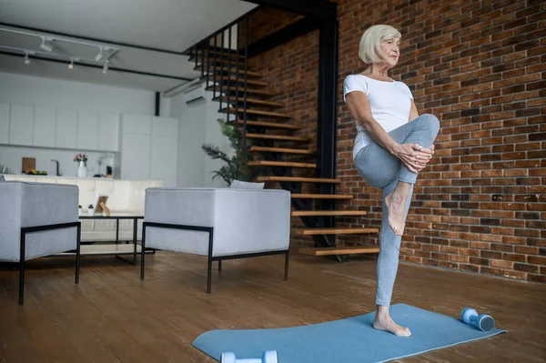 A senior woman doing balancing asana and looking concentrated — 스톡 사진
