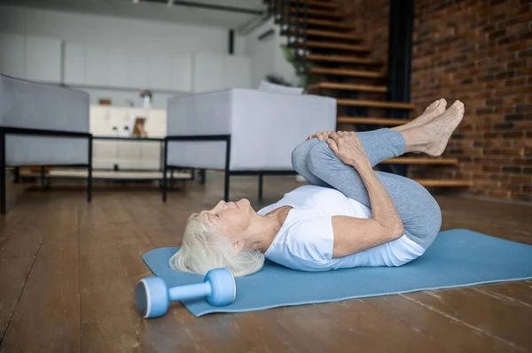 An elderly lady doing yoga at home — Stockfoto