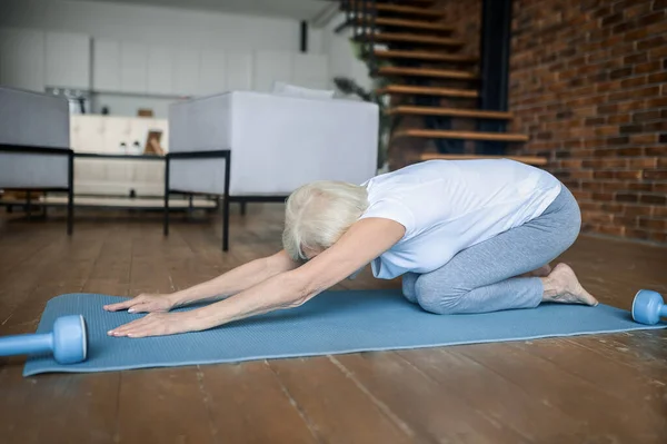 A woman laying on the floor in a child pose — 스톡 사진