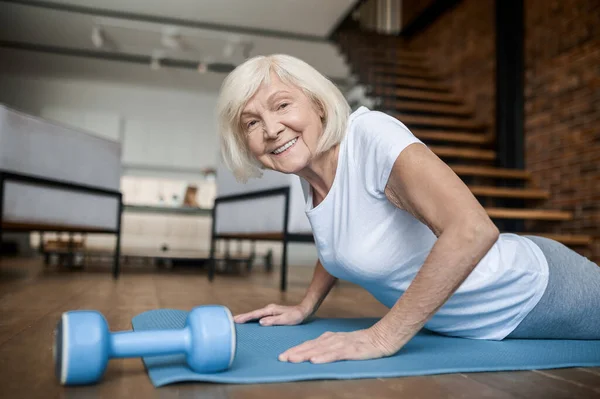Aktive Seniorin im weißen T-Shirt beim Planken — Stockfoto
