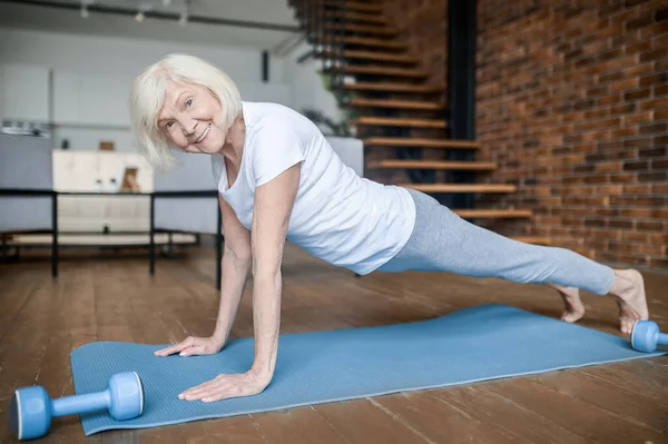 Senior active woman in a white tshirt doing plank — Stock Photo, Image