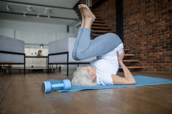 날씬하고 활동적 인 연로 한 여자 가 바닥에서 아스파라거스를 하고 있다 — 스톡 사진