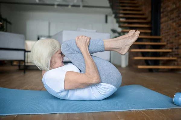 Eine Frau macht Übungen auf der Yogamatte — Stockfoto