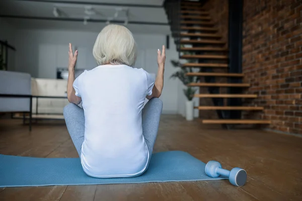 A woman doing exercises while sitting on the yoga mat — 스톡 사진