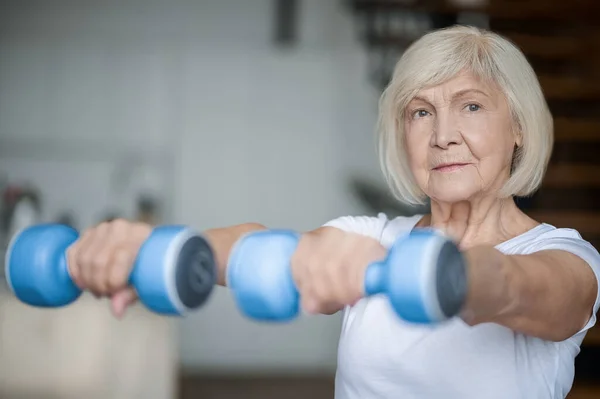 Active senior woman with dumbbells in hands doing her workout — Stok fotoğraf