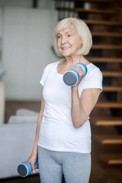 Short-haired senior woman exercising with dumbbells — Stockfoto