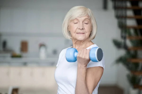 Short-haired senior woman exercising with dumbbells — Stockfoto