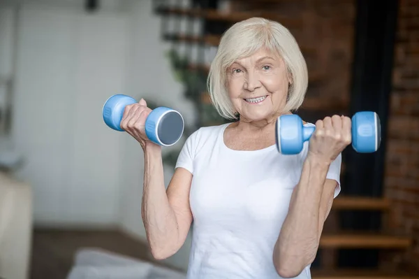 Mulher idosa de cabelos curtos se exercitando com halteres — Fotografia de Stock