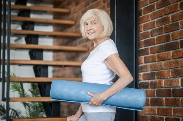 Slim senior woman with yoga mat in hands — Stok fotoğraf