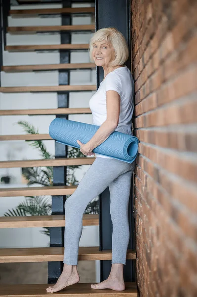 Slim senior woman with yoga mat in hands — 스톡 사진