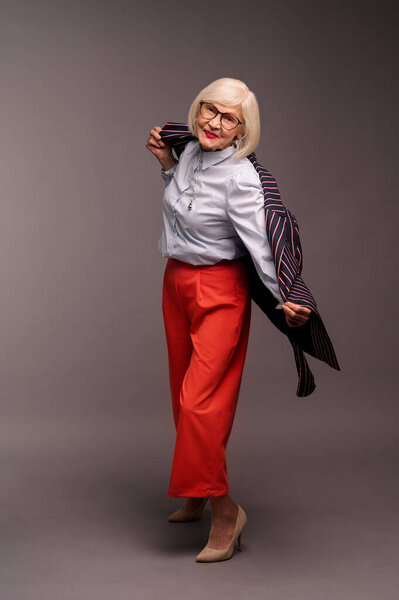 Blonde senior elegant woman in red pants and stylish jacket