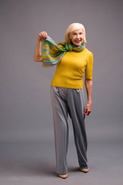 Senior woman in yellow shirt and with a green scarf
