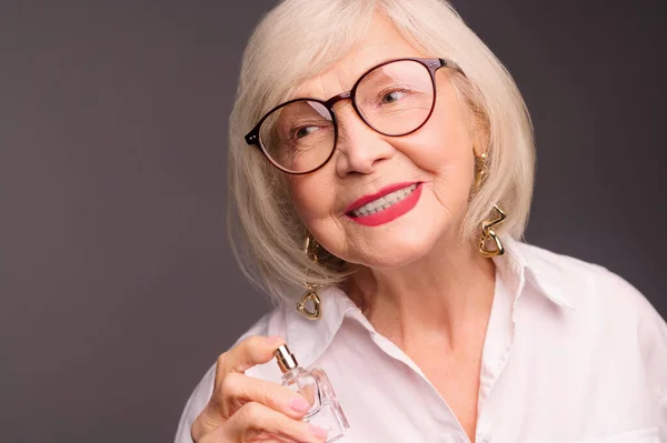 Waist up of senior woman with a perfume in hands