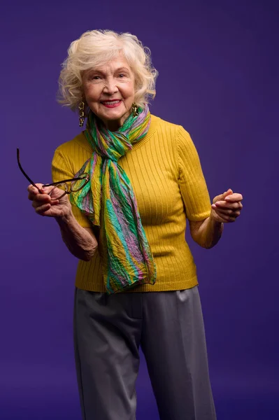 Mujer mayor en camisa amarilla y con una bufanda verde sin preocupaciones — Foto de Stock