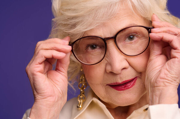 Elegant senior lady in eyeglasses in beige shirt