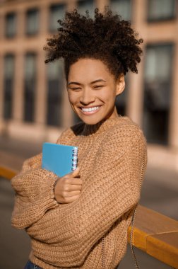 Parlayan kız dışarıda egzersiz kitabına sarılıyor.