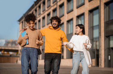 Adam ve iki kız sokakta yürürken gülüyorlar.