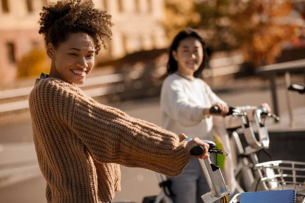 Mulatto女の子とアジアのガールフレンドとともに自転車で路上 — ストック写真