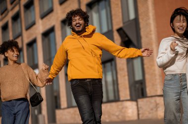 Mutlu adam ve iki kız cadde boyunca ilerliyorlar.