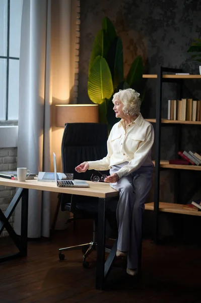 Masada oturmuş dizüstü bilgisayara bakan bir kadın. — Stok fotoğraf