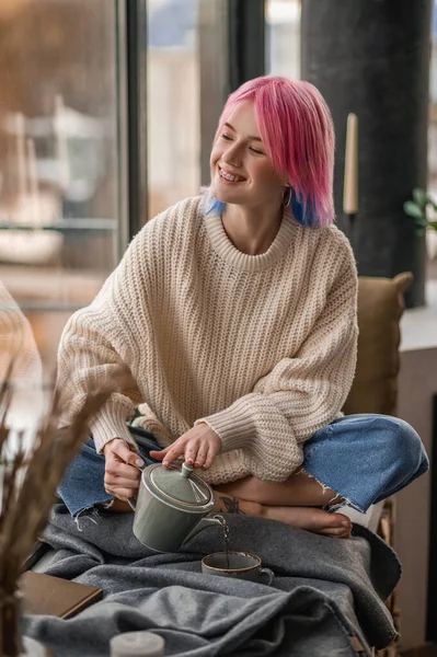 하얀 스웨터를 입고 아침에 찻잔에 차를 붓는 소녀 — 스톡 사진