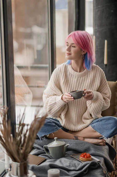 분홍색 머리를 하고 창가에서 차를 마시고 있는 소녀 — 스톡 사진