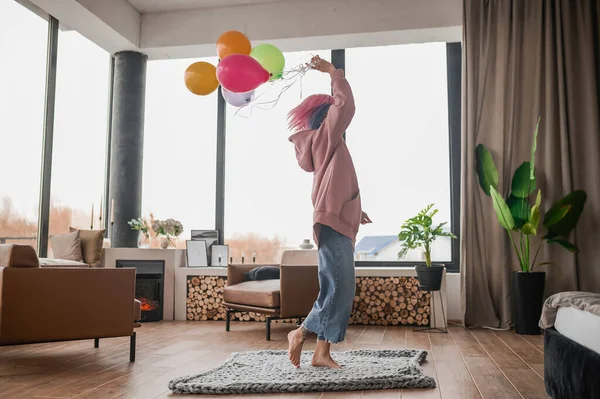 Ein fröhliches Mädchen tanzt mit einem Haufen bunter Luftballons — Stockfoto