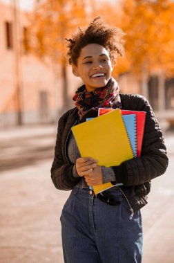 Elinde kitaplarla sokakta yürüyen bir kız.