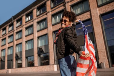 Elinde Amerikan bayrağı olan esmer tenli bir kız.