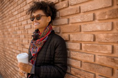 Güneş gözlüklü hoş bir kız dışarıda kahve içiyor.