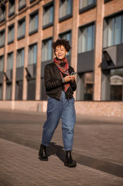 Темноволосая молодая девушка в куртке и джинсах на улице — стоковое фото