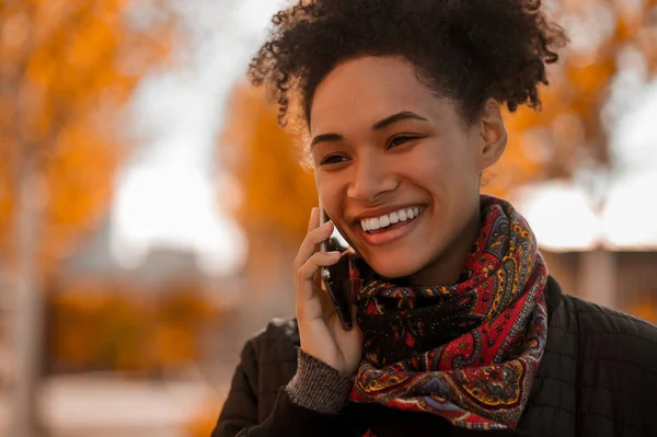 Kudrnatá usměvavá dívka mluví po telefonu — Stock fotografie