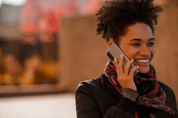 Kudrnatá usměvavá dívka mluví po telefonu — Stock fotografie