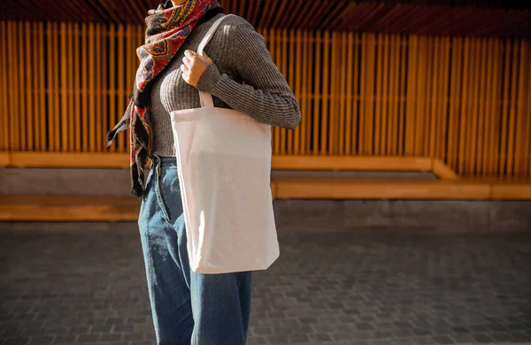 Μια νεαρή γυναίκα με μια τσάντα λινό στέκεται στο δρόμο — Φωτογραφία Αρχείου