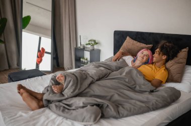 Genç çift yatakta yatarken kendilerini rahat ve yakın hissediyorlar.