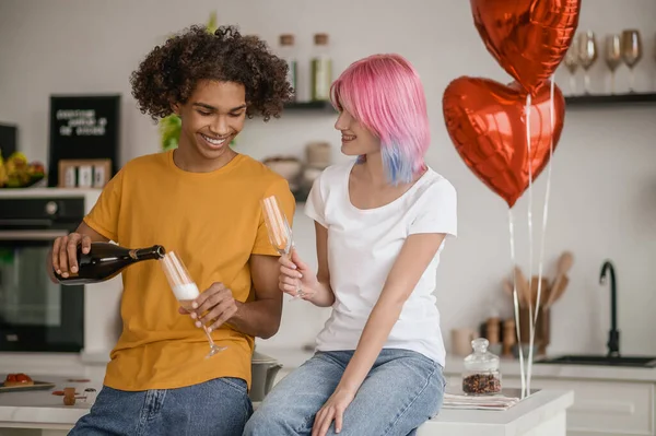 Usmívající se mladý muž nalévá šampaňské na své přítelkyně sklo — Stock fotografie