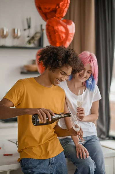 Usmívající se mladý muž nalévá šampaňské na své přítelkyně sklo — Stock fotografie