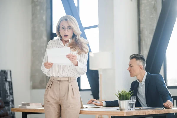 Blonde woman reading something and looking surprised — Stock Photo, Image