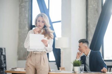 Sarışın kadın bir şeyler okuyor ve üzgün görünüyor.