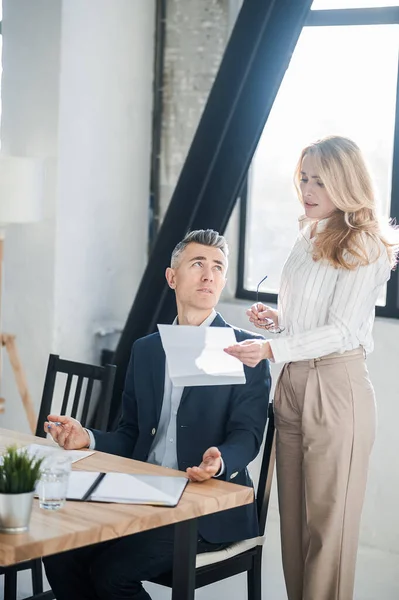 Blonde woman showing na document to her boss — Stock Photo, Image