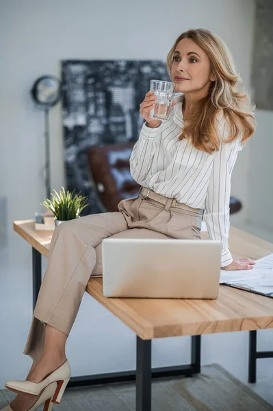 A cute woman sitting on the table in the offcie — Stock Photo, Image