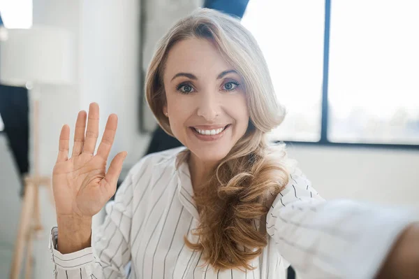 Blonde Frau lächelt und winkt mit der Hand — Stockfoto