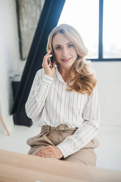 A blone businesswoman in her office talking on the phone — Stock Photo, Image