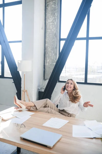 A blone businesswoman in her office talking on the phone — Stock Photo, Image